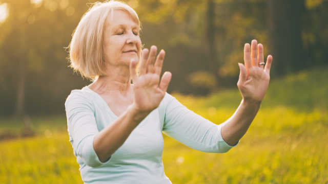 Older blonde woman doing tai chi with eyes closed